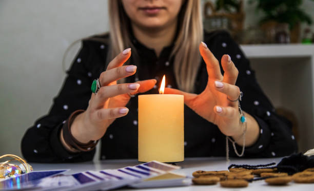 istock Woman fortune teller fortune telling on a candle. Selective focus. 1455473280