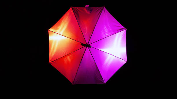 istock Colorful illuminated umbrella isolated on a dark background 1455473559