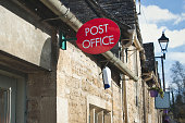 Building exterior showing a red post office sign in a rural village in England