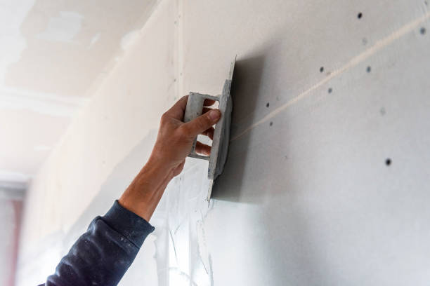 old manual worker with wall plastering tools renovating house. - plaster imagens e fotografias de stock