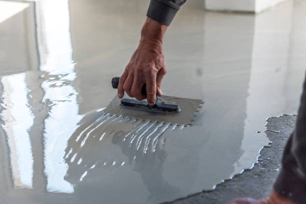 istock Grey self-leveling screed, new floor layer, man hand. 1455477058