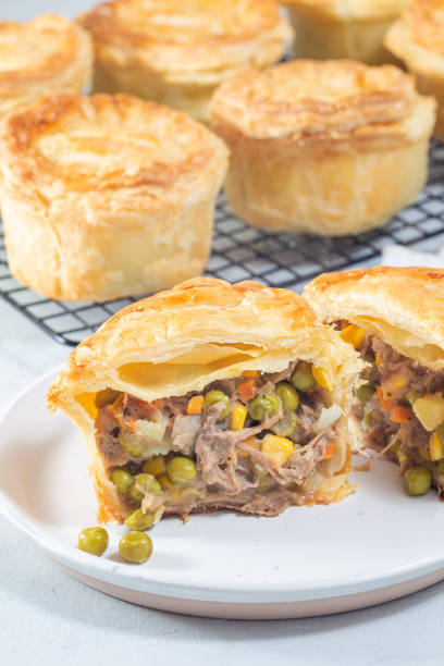 istock Sliced beef pot pie on plate, pies on cooling rack, vertical 1455478867