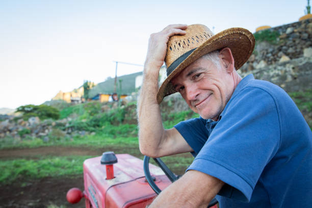 istock Smiling farmer holds his cowboy hat while sitting on his tractor 1455479328