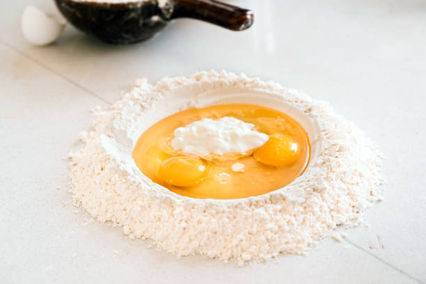 Pile of flour with egg yolks for dough on table