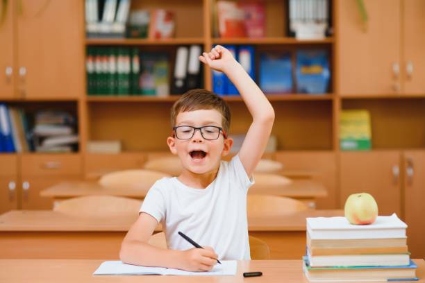 istock Elementary school boy at classroom desk trying to find new ideas for schoolwork. 1455481004