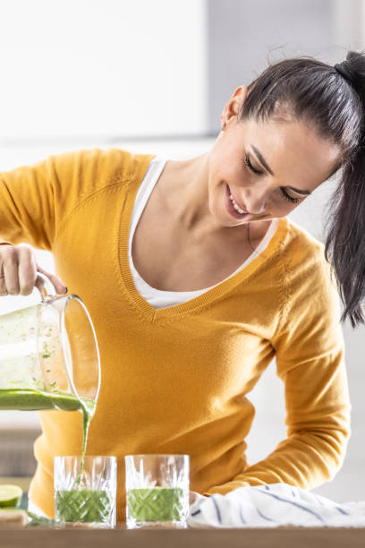 istock A woman pours the finished spinach smoothie into two glasses from a blender. 1455482390
