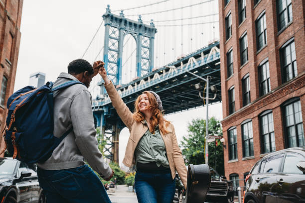 A multi-ethnic couple is dancing in Brooklyn with Manhattan Bridge in the background A multi-ethnic couple is dancing in Brooklyn with Manhattan Bridge in the background. They are in Dumbo, a famous district in New York City. valentines day holiday stock pictures, royalty-free photos & images