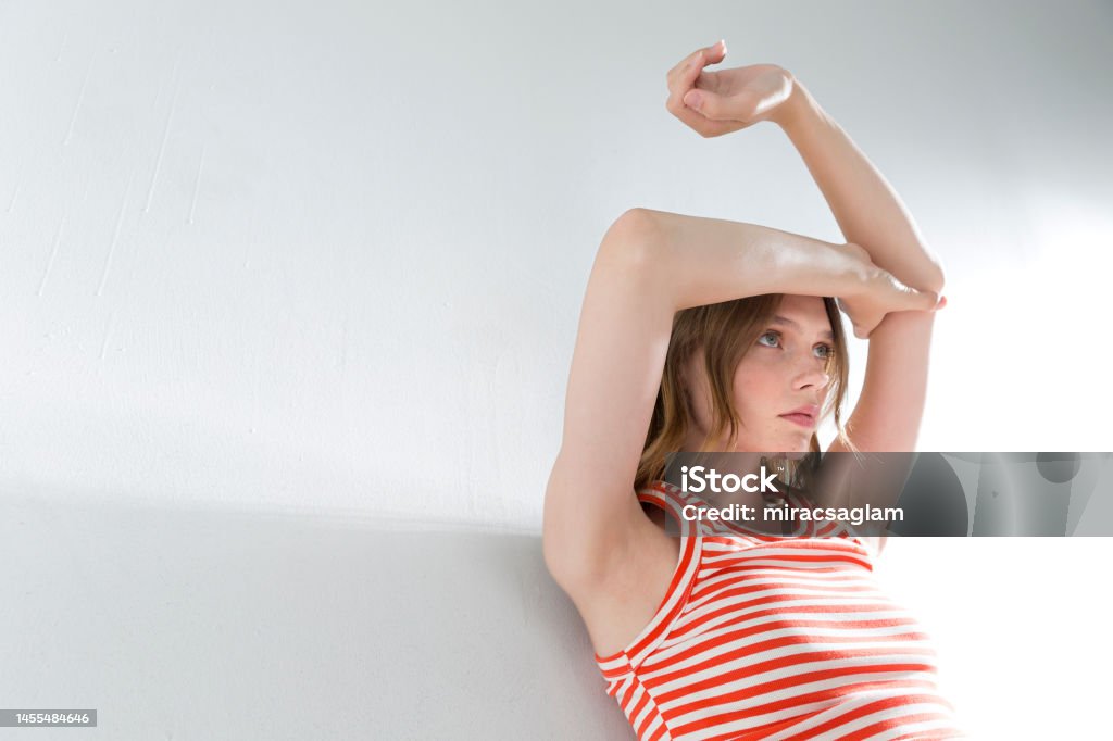 Girl on a white bA blonde and freckled girl on a white background, wearing a striped orange t-shirt.ackground, wearing a short-sleeved t-shirt. A blonde and freckled girl on a white background, wearing a striped orange t-shirt. 20-24 Years Stock Photo