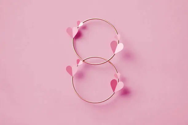 Heart shapes over gold colored circles forming number 8 on pink background. March 8 - International Women's Day concept. Horizontal composition with copy space.