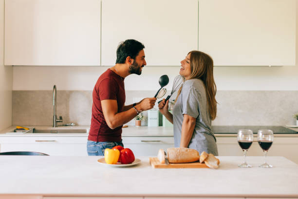istock happy caucasian couple dancing and singing using ladle in home kitchen 1455486198