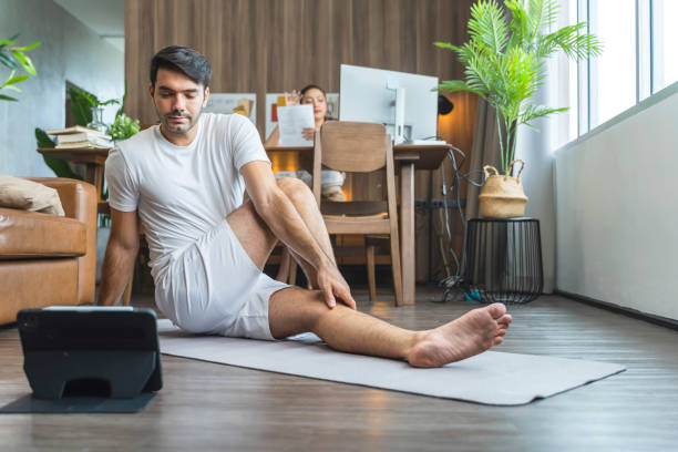 istock young asian male husband train yoga exercise workout practicing from online lesson at living room with wife working at behind,working from home stay home state order lifestyle concept 1455487875