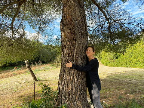 Woman hugging a forest tree