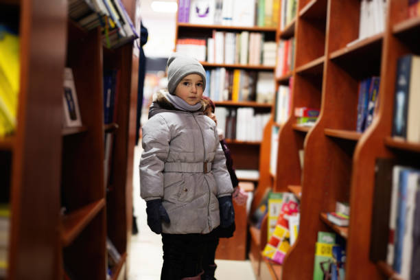 istock Little cute sisters in jacket reaching a book from bookshelf at the library. Learning and education of european girl kid. 1455488533