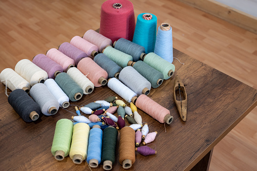 Colorful weaving threads on a wooden table.