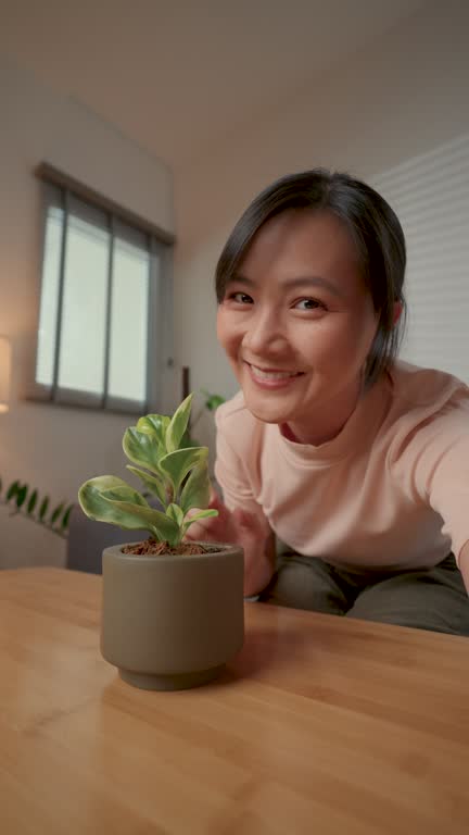 Asian woman using smart phone for video call or live streaming in living room at home.