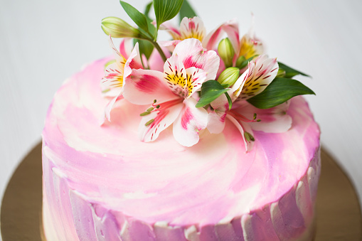 Carrot cake with pink glaze, beautiful flowers and edible silver as a decoration