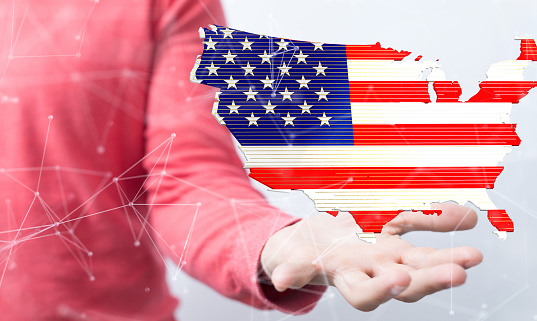 A shallow focus of human hands holding the flag of the USA in the form of a map