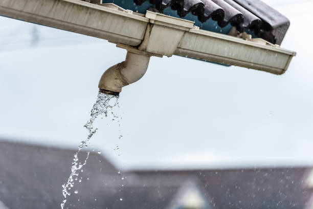 istock Rain water flowing down from old plastic roof gutter in rainy day. 1455492306