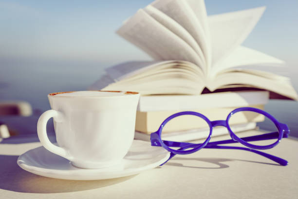 Cup and open book on nightstand.