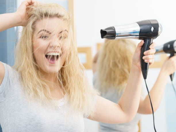 istock Blonde woman using hair dryer 1455495550