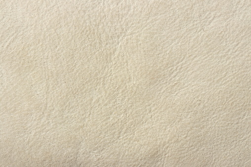 Genuine leather (sheepskin) with beige surface, texture animal skin. Background with copy space for text or product due to nice yellow pattern. Authenticity and true natural design of grey light its.