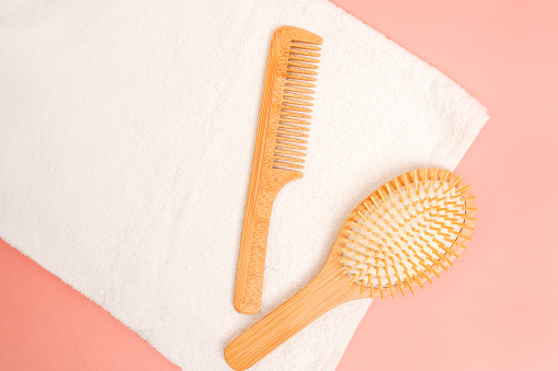 Pair of two hair brushes made from wood on white towel on pink background