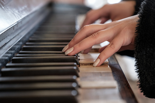 Close-up shot of young female hands on antique piano keys