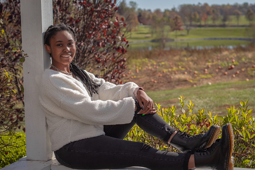A portrait of a beautiful young black woman sitting in a field in autumn