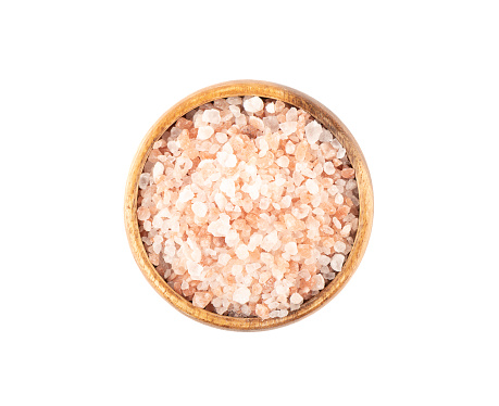 Top view of pink Himalayan salt in a wooden bowl. White background, copy space.