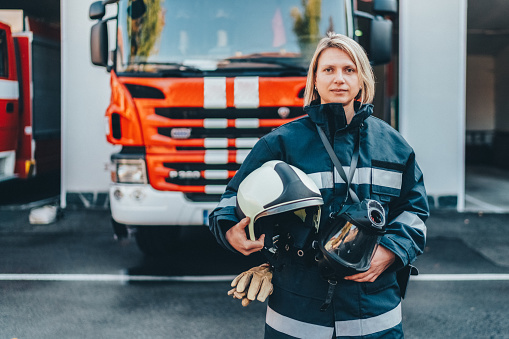 Female firefighter with work helmet under arm looking at camera