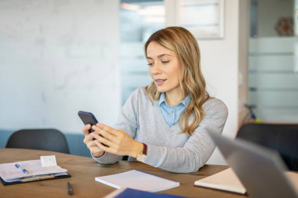 istock Businesswoman sitting at desk and text messaging while working at office. 1455506950