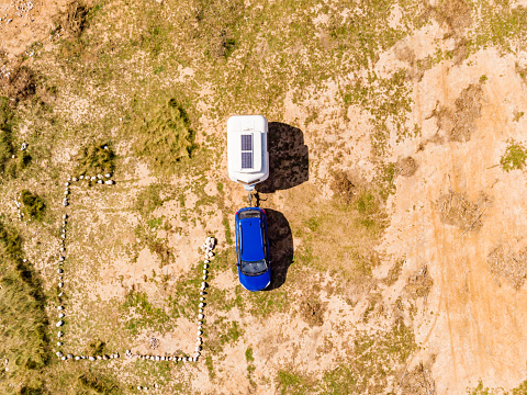 Aerial view, coastal landscape with caravan trailer wild camping on beach sea shore. Mediterranean coast of Spain. Holidays, traveling with motorhome.