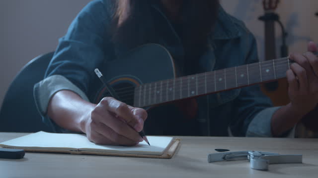 Close up on asian musician hand writing a song in notebooks