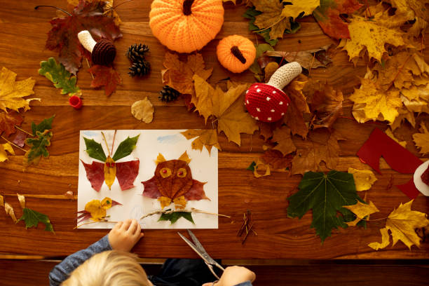 istock Child, applying leaves using glue, scissors, and paint, while doing arts and crafts at home 1455507706
