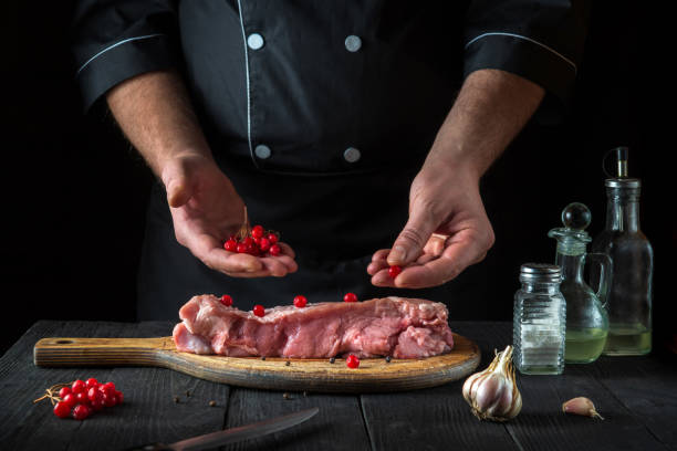 dans le restaurant, le chef de cuisine prépare de la viande de veau crue. avant la cuisson, le cuisinier met la viorne sur le bœuf. plat national - veal calf meat baking photos et images de collection