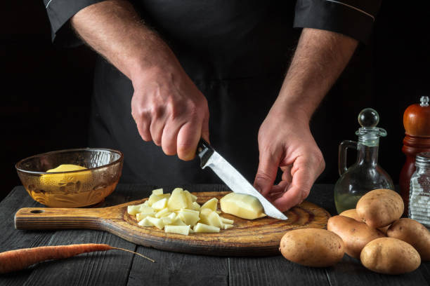 istock The chef cuts raw potatoes into pieces with a knife before preparing breakfast or dinner. Close-up of a cook hands while working in a restaurant kitchen. 1455507801