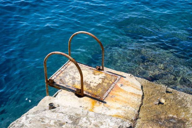 rusty metal steps on concrete platform to blue Mediterranean sea in Capri, Italy