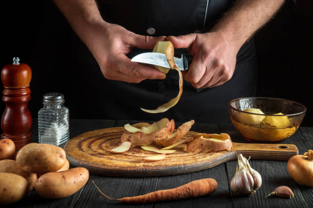 istock The chef peels raw potatoes in a restaurant kitchen before preparing a national dish. Close-up of a cook hands with a knife while working 1455508038