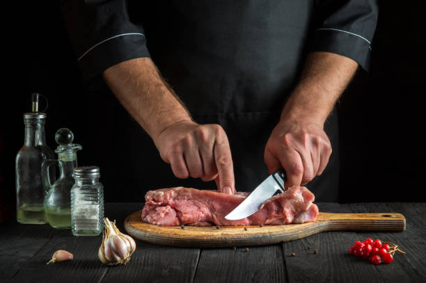 istock The cook cuts meat with a knife before baking. Spices on the kitchen table in a restaurant for preparing a delicious lunch. 1455508045