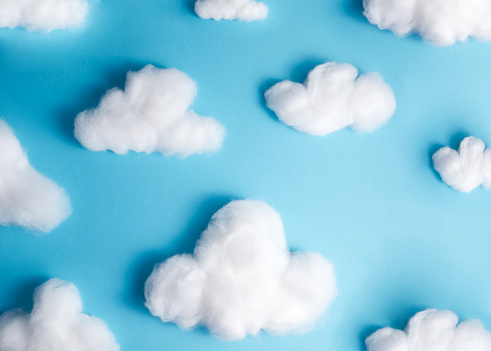 Pattern of white fluffy clouds made of cotton wool on a blue background