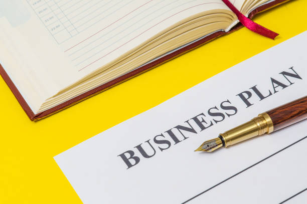 istock Office still life on yellow table with a gilt pen, notebook and business plan preparing for notes 1455510424