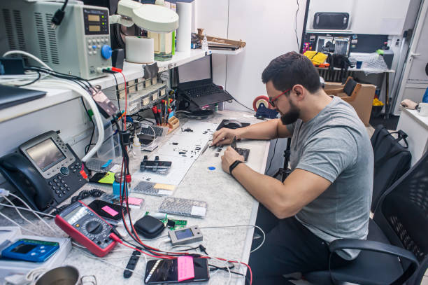 istock Electronics repair shop, technician is surrounded by tools and equipment. 1455512189