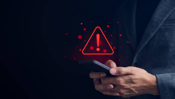 uomo d'affari o utente che tiene lo smartphone con il segnale di avvertimento triangolare rosso per l'errore di notifica e il concetto di manutenzione. segnale esclamativo di avvertimento, - mistake error message internet failure foto e immagini stock