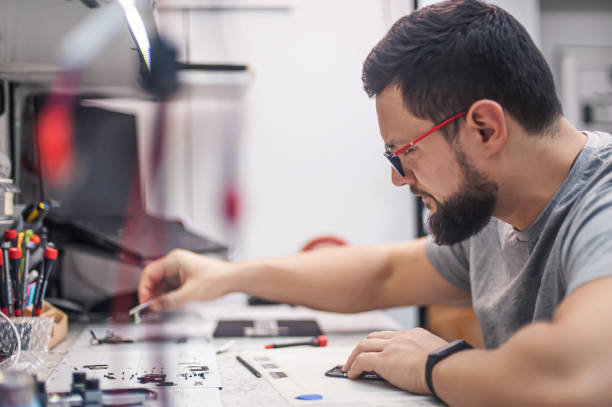 istock Electronics repair shop, technician is surrounded by tools and equipment. 1455512304