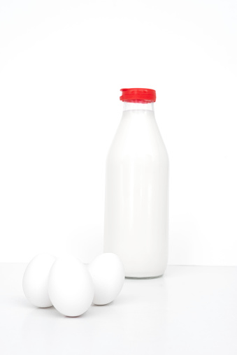 Three organic white eggs with daily fresh milk isolated on white, vertical
