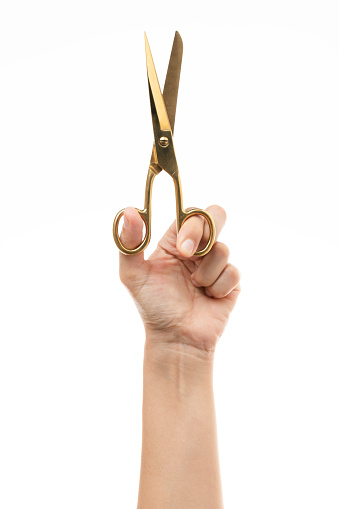 Hand is holding golden  scissors on pure white background.
