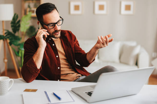 istock Young man talking on the phone in home office 1455523872