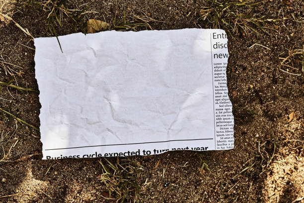 istock Cutting from a newspaper, isolated on white, with plenty of space for your copy, lying discarded in the dirt 1455526867