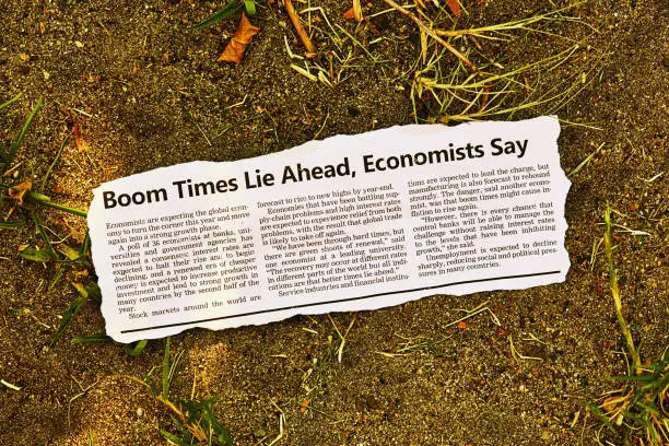 Photo of Optimistic news article about economic recovery being just around the corner, ironically lying discarded in the dirt