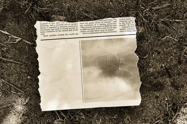 Photo of Cutting from a newspaper, isolated on white, with plenty of space for your copy, lying discarded in the dirt